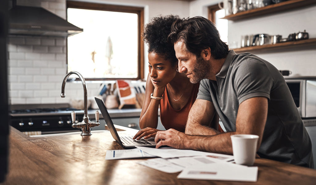 Middle aged couple reviewing documents and on their computer Middle aged couple reviewing documents and on their computer