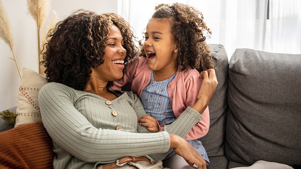 Mother and daughter laughing on couch