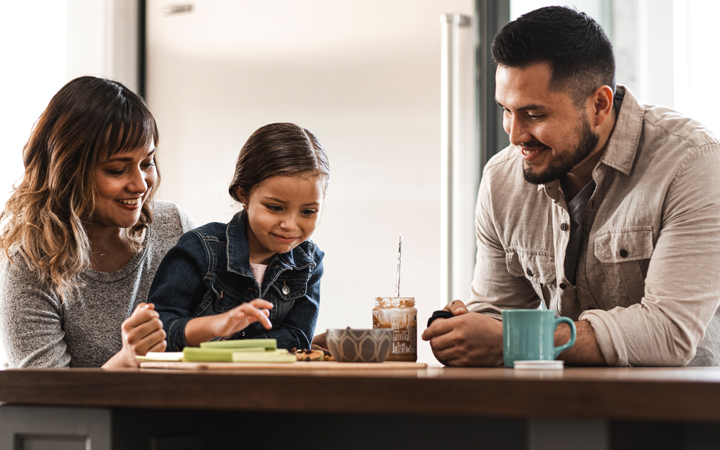 Small family, mother daughter and father, sharing a healthy snack at the table.