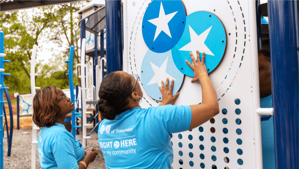 Two BlueCross volunteers putting BlueCross Healthy Place playground structures together.