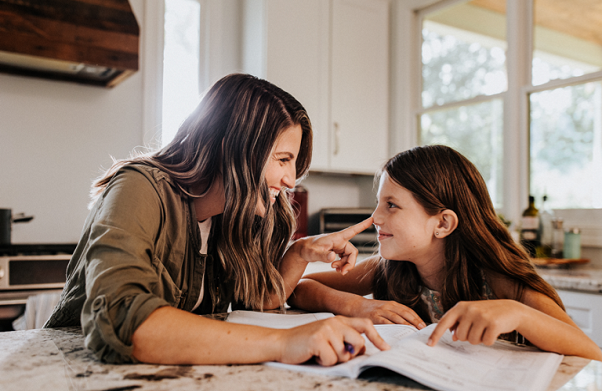 Mother and daughter playing while reading a book