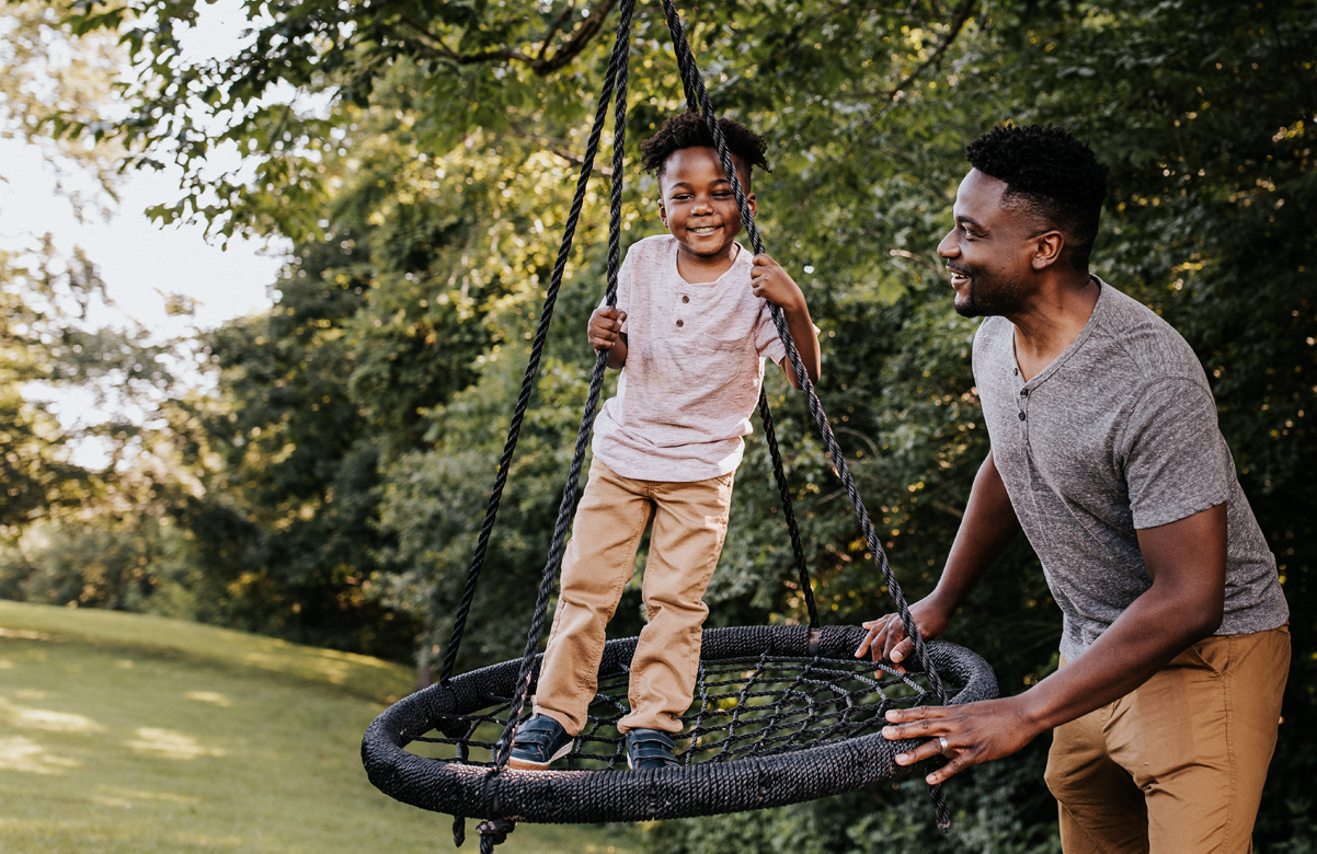 Man pushing child on swing.