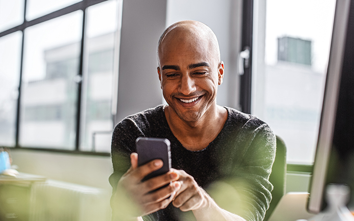 Man smiling as he looks at his smart phone