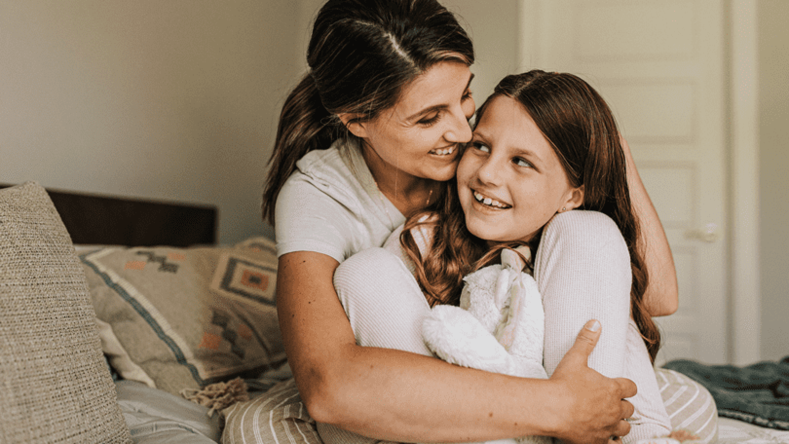 Mother holding and hugging her daughter as they smile