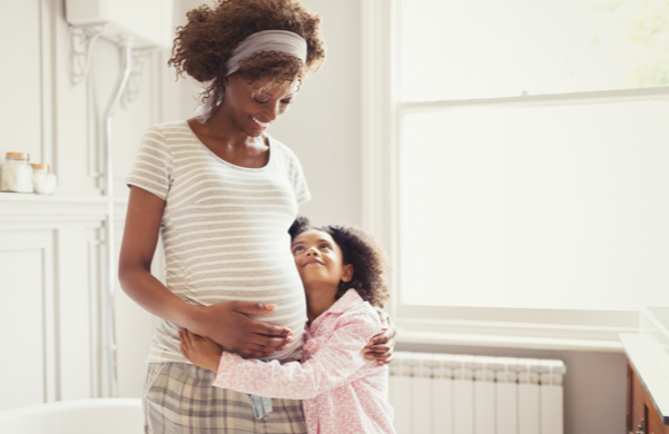 Pregnant mother hugging her young child Pregnant mother hugging her young child