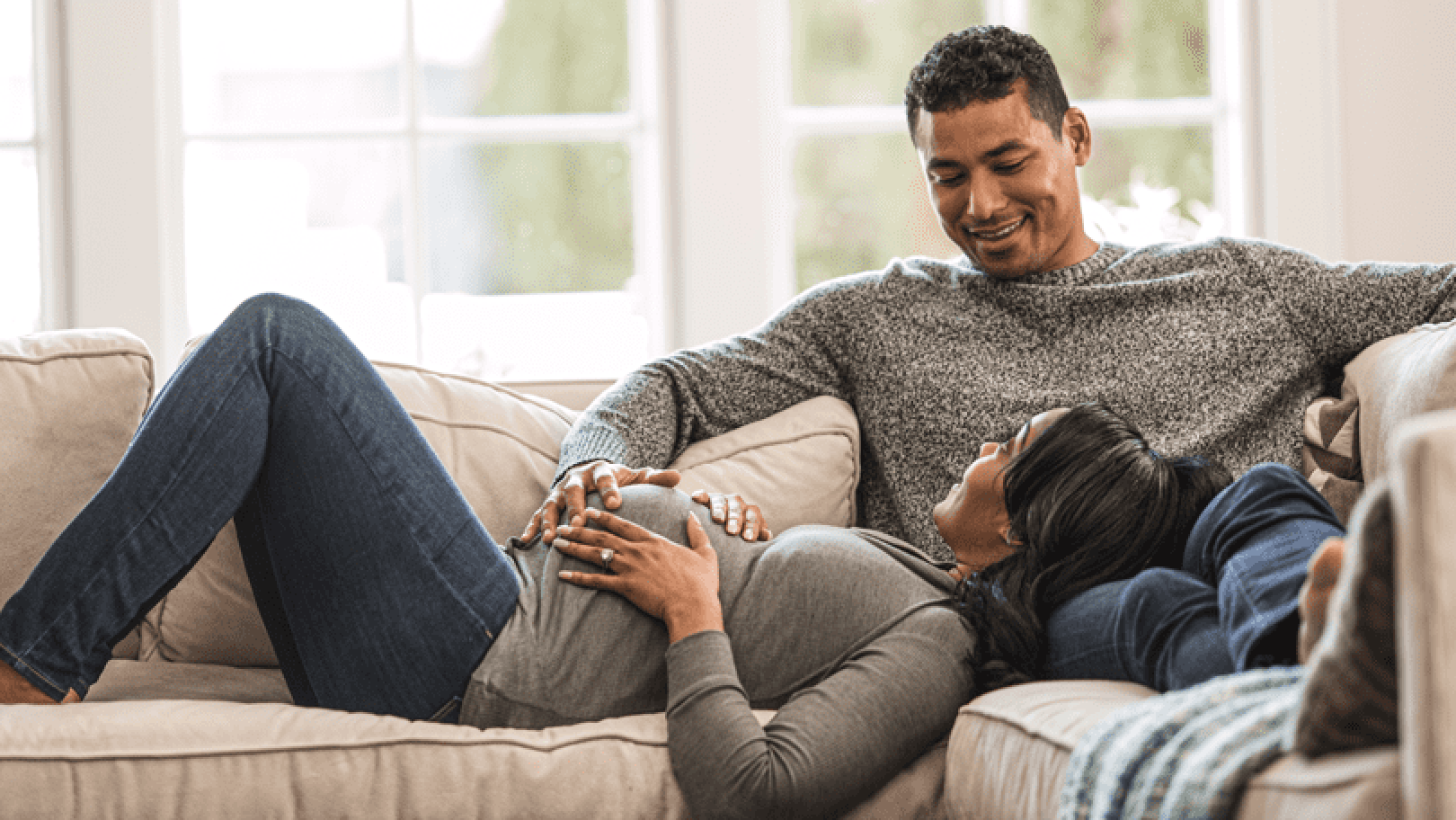 Pregnant woman and her partner sitting on the couch together