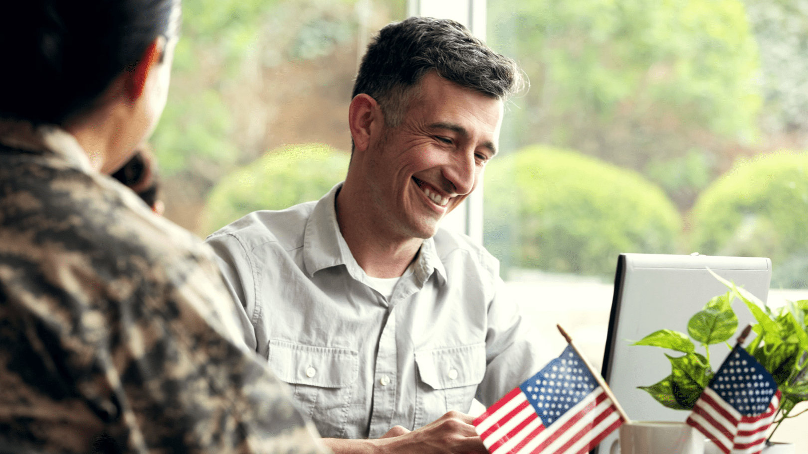 A man looking at a computer assisting a military or veteran person.