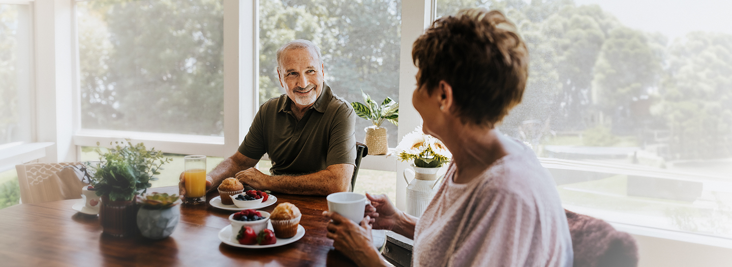 Elderly couple at breakfast table smiling at each other