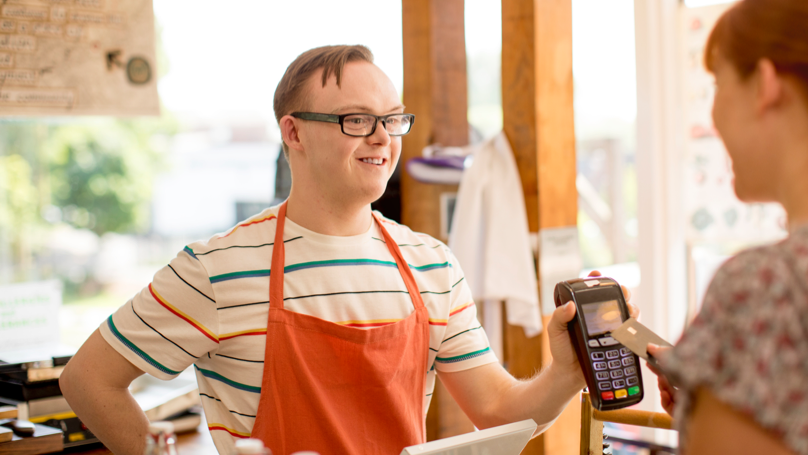 A young man at a grocery store assisting a customer A young man at a grocery store assisting a customer